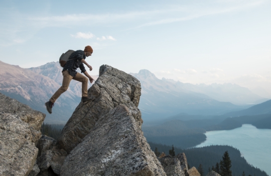 Un homme debout sur une montagne rocheuse surplombant un lac.