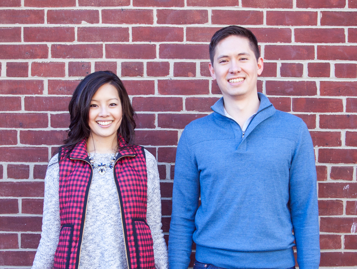 Co-founders of TilesInspired are standing up smiling in front of a brick wall.