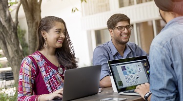 Des exportateurs canado-indiens souriants se réunissent en plein air à un bureau debout