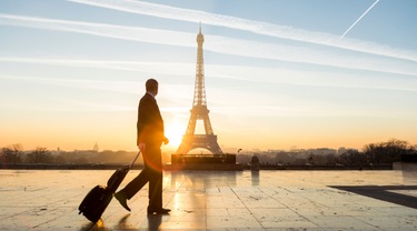 Magnifique lever de soleil sur Paris avec la tour Eiffel en arrière-plan, tandis qu’un homme d’affaires marche avec ses bagages.