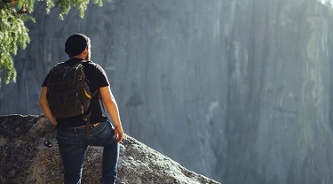 Male hiker prepares to cross a chasm.