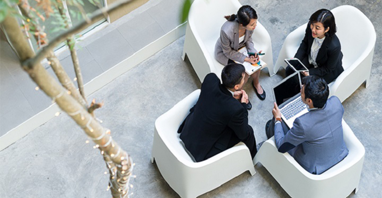 a group of coworkers are sitting in round holding a discussion