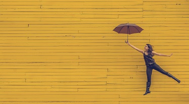 Woman jumping in the air with an umbrella over her head