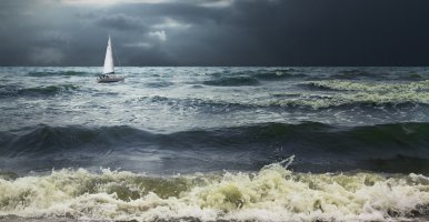Lonely white sailboat in stormy seas with dramatic skies