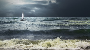 Lonely white sailboat in stormy seas with dramatic skies
