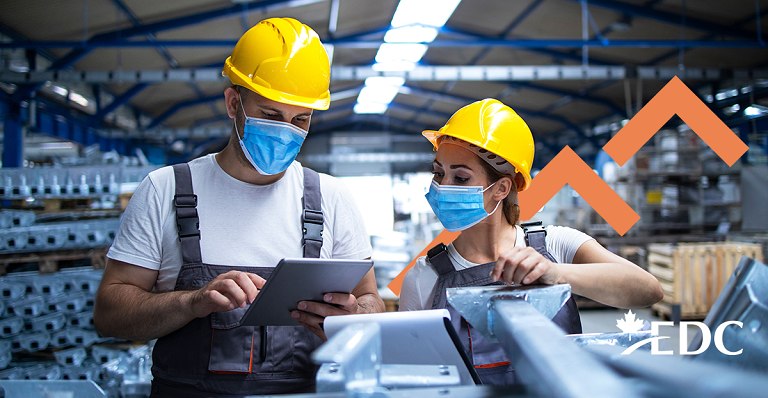 Un homme vêtu d’un manteau rouge du fabricant canadien Wuxly transporte un bâton et des patins de hockey.