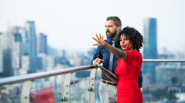 Two individuals talking outside and looking at the horizon. 