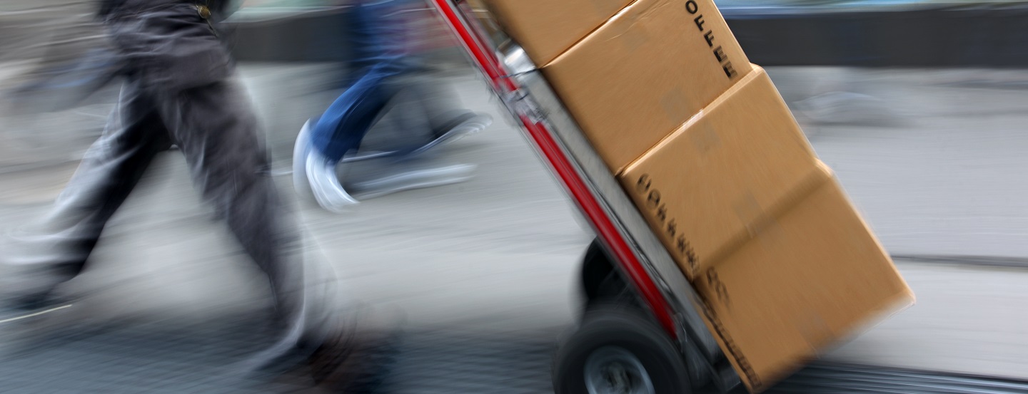 Worker moves stack of boxes on a hand dolly