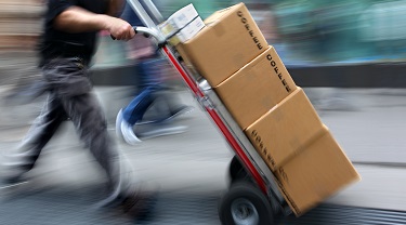 Worker moves stack of boxes on a hand dolly