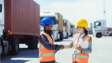 Un homme et une femme portant un casque de sécurité sourient en se serrant la main