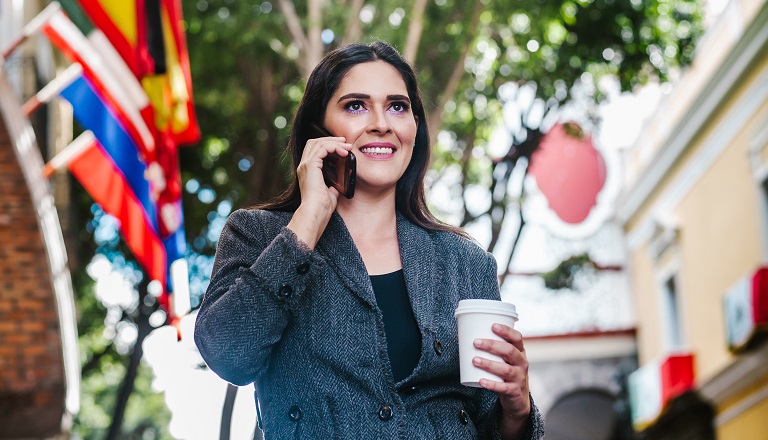 Latin businesswoman in street with international flags overhead.