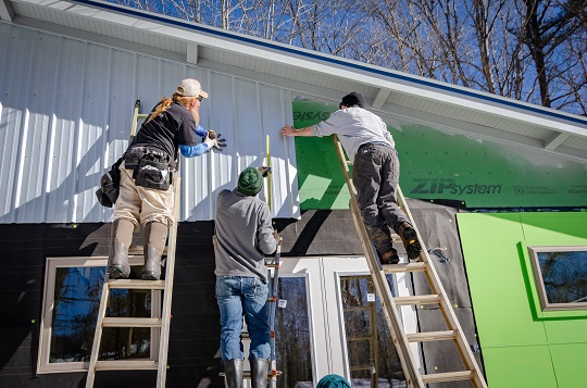 Three men building a house