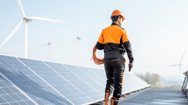 Man in orange hardhat among solar panels