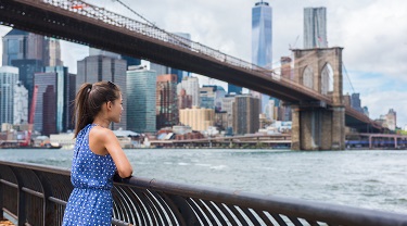 Female entrepreneur in NYC looks out over the river under Brooklyn Bridge