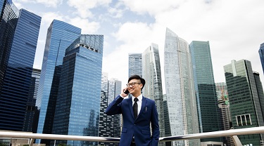 Smiling Asian man stands in front of Bangkok skyscrapers