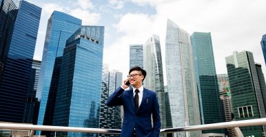 Smiling Asian man stands in front of Bangkok skyscrapers
