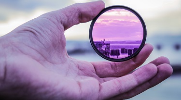 A hand holding a lens up to the horizon