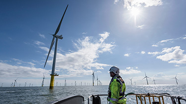 A worker looking out from ship to offshore wind farm 