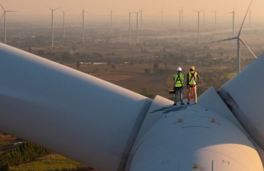 Two technicians standing on a wind turbine.