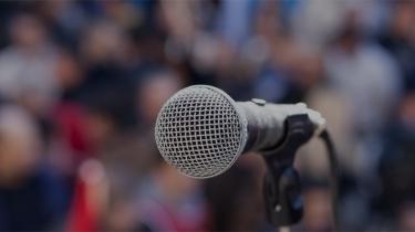 Microphone in front of a shaded crowd represents political risks to business that aren't always obvious.