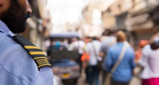 Un agent de sécurité surveille la foule d’un marché extérieur achalandé.