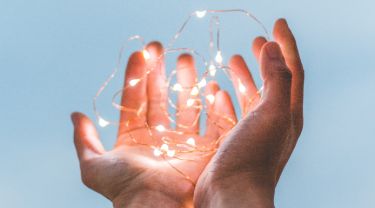 Two hands holding a string of tiny lights.