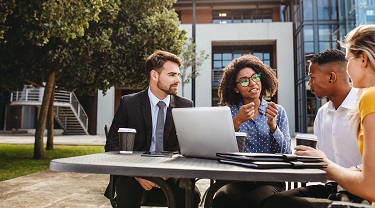 Installée à une table à l’extérieur, une dirigeante explique la nouvelle stratégie d’affaires à son équipe.