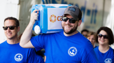 Bearded man in blue shirt carrying CARE water jug