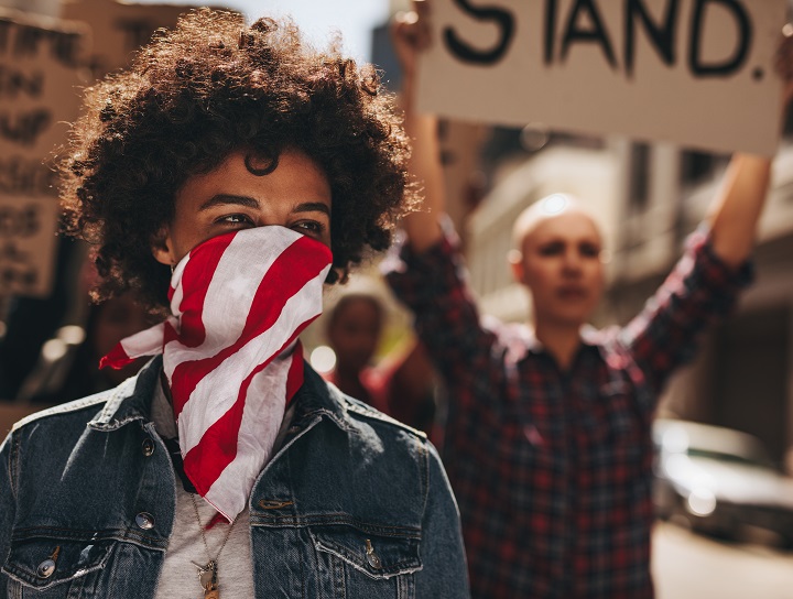 Un militant afro-américain manifeste avec un foulard sur la bouche.