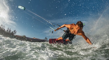 Action shot of man kiteboarding among waves 