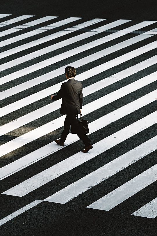 Man with briefcase walking down a striped road.