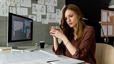 A woman looks determined and confident at her desk.