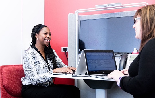 Two smiling EDC employees working at computers