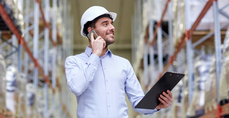 Man in hardhat with cellphone and clipboard