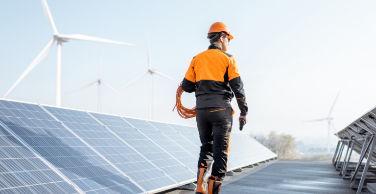 Man in orange hardhat among solar panels