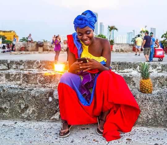 Une Colombienne en costume traditionnel tenant son téléphone cellulaire.