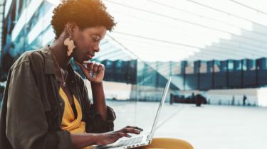 Une entrepreneure noire à l'air pensif examine son portable.