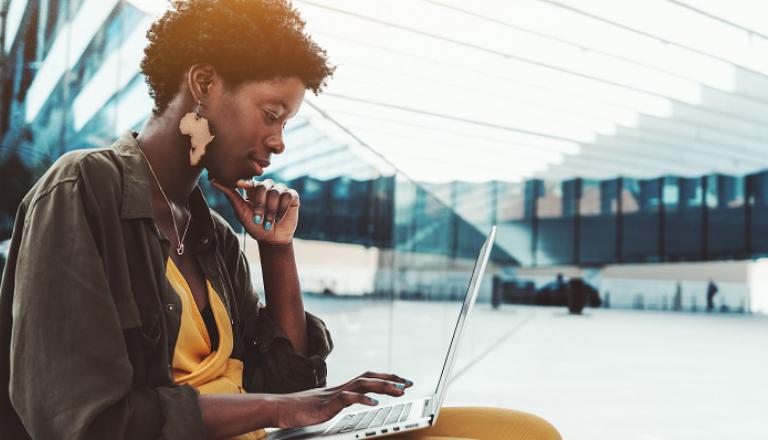 A pensive black female entrepreneur studies her laptop