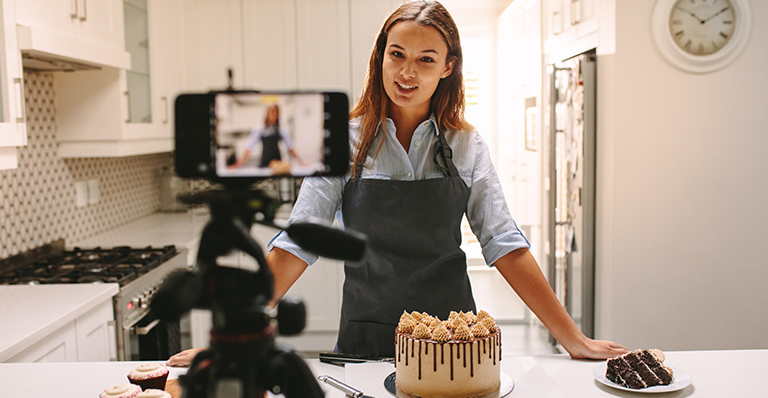 A chef is recording her cooking show with her cellular.