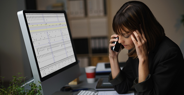 An accountant working on her spreadsheet is talking on her cellular.