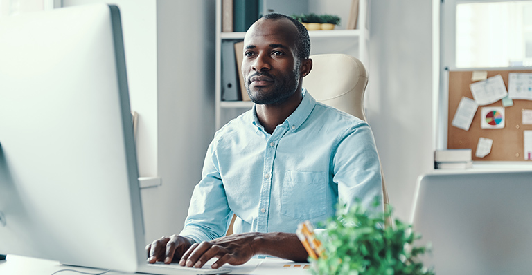 A businessman is typing a report on his computer.