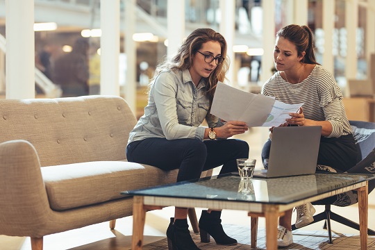 Professional women consulting each other, reports and computer