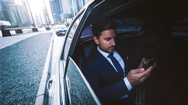 Worried businessman checks phone while driving in a limo