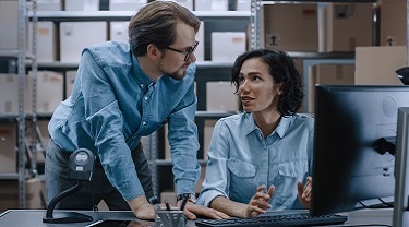 Two colleagues consult with each other in a warehouse. 