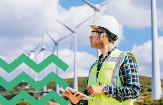 Man in green vest by wind turbines