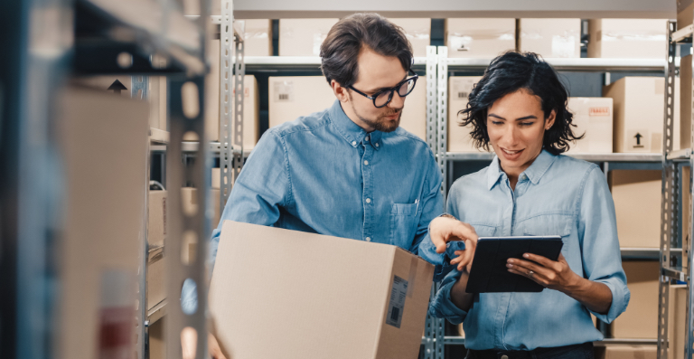 Man and woman checking clipboard in warehouse