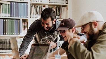 Team laughing and working around a desk.