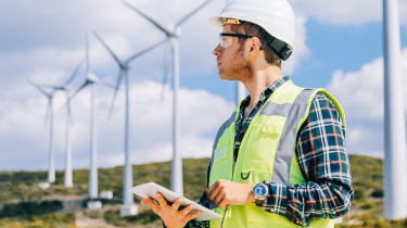 Man in green vest by wind turbines