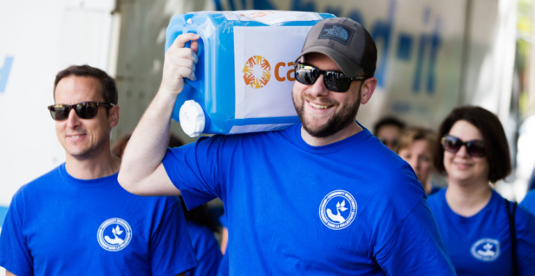 Bearded man in blue shirt carrying CARE water jug