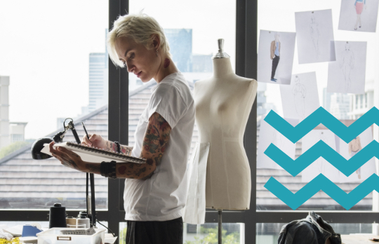 Fashion designer standing in her studio sketching on an art pad